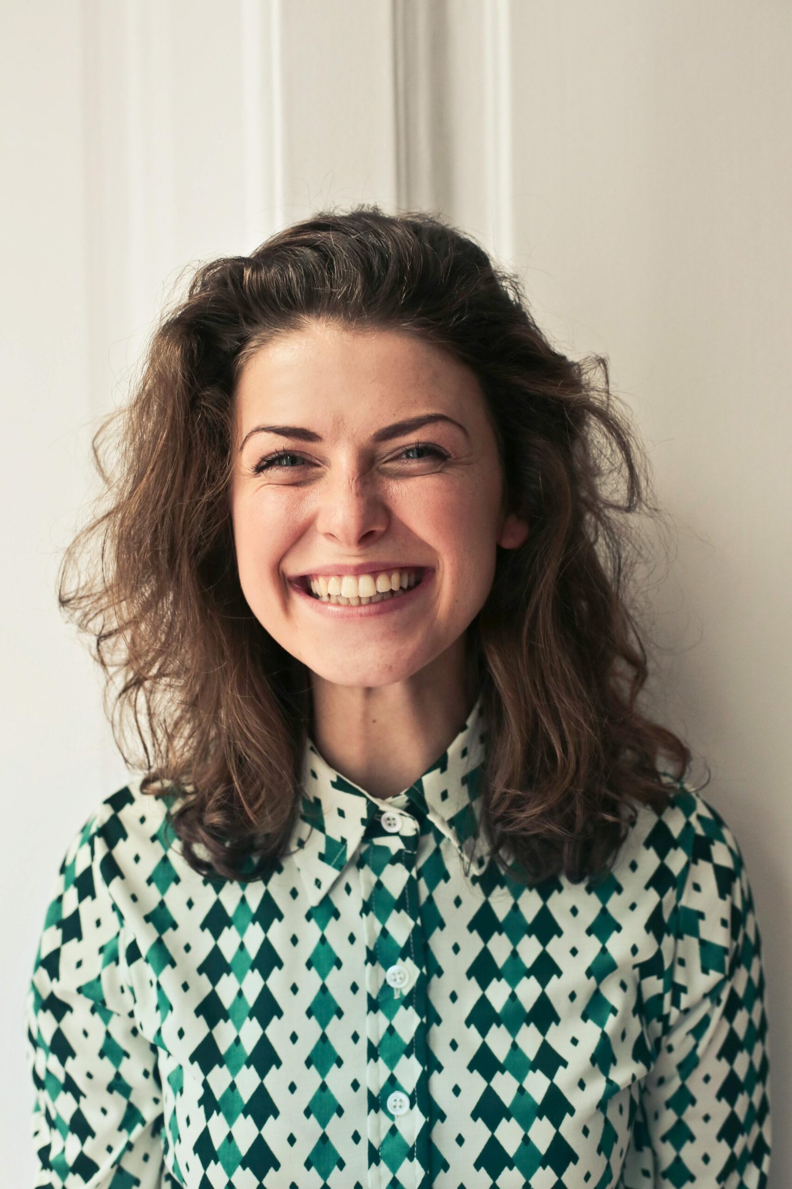 Home Portrait of a joyful brunette woman with a vibrant smile indoors, capturing happiness and positivity.